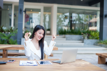 young Asia modern successful business woman holding a gold bitcoin Computer , and a tablet ,...