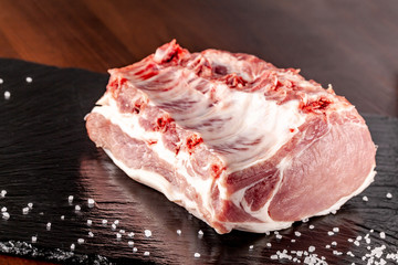Raw meat pork. Tenderloin on the bone. ribs. on a black background. salt on the table.