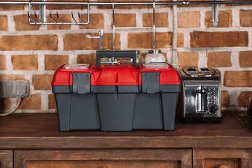 close-up shot of toolbox standing on kitchen table with toaster in front of brick wall