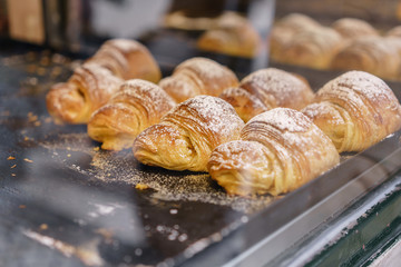many of croissants. Hot pastries lie on the shelf in the cafe. Buns and bagels in the store.
