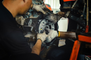 mechanic tractor working under the car and changing clutch at car repair shop tractor