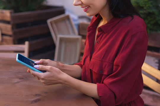 Weather forecast. Modern smiling woman feeling curious while checking weather forecast on her smart phone