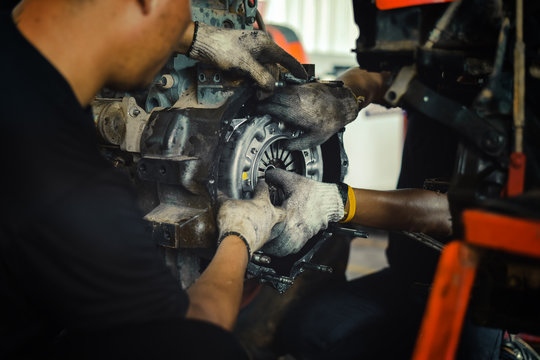 mechanic tractor working under the car and changing clutch at car repair shop tractor