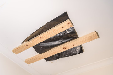 House maintenance concept. Ceiling crack was covered by black plastic sheet with screws to prevent collaps.