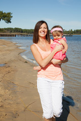 modern single mother on sand beach walk with baby girl