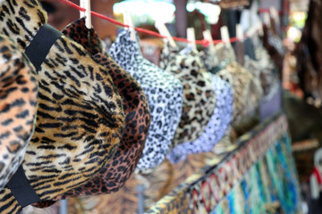 Fototapeta na wymiar Tiger pattern fabric of cap and hat hanging on the line for sale in the local market.