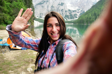 Portrait of a beautiful woman (girl) taking a selfie with the lake and the mountains in the...