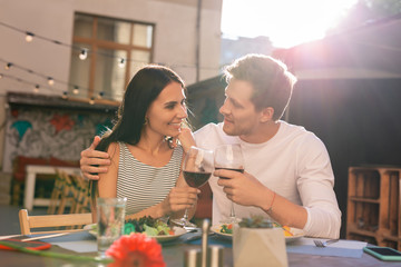 Glasses of wine. Happy young couple feeling loved and excited while clanging their glasses of red wine during romantic dinner