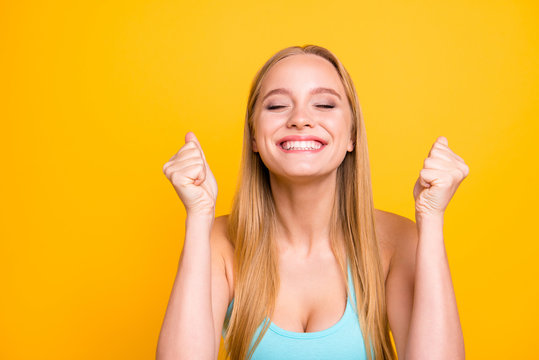 Dynamic image of human facial emotions concept. Happy woman celebrating being of victory clasps her hands into fist and make big smile. Female model isolated on yellow background