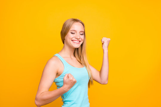 Finally yes! Happy woman celebrating being of victory clasps her hands into fist and make big smile, stands half a turn and isolated on yellow background with copy space