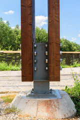 detail of massive wood post anchored with special metal connector using nuts and bolts to a solid isolated concrete foundation base © Florin
