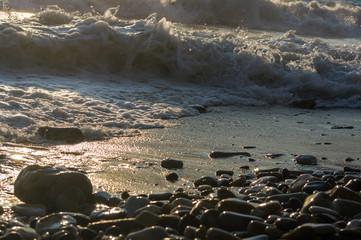 pebble stones on the sea beach, the rolling waves of the sea with foam