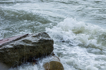 pebble stones on the sea beach, the rolling waves of the sea with foam