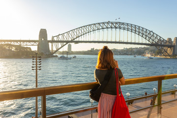 Female tourist with backpack bag  taking photos of Sydney Harbour Bridge during summer vacation...