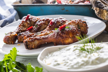 Grilled roasted and barbecue chicken legs on white plate.