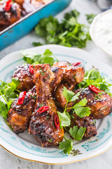 Grilled roasted and barbecue chicken legs on white plate.