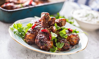Grilled roasted and barbecue chicken legs on white plate.