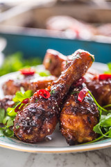 Grilled roasted and barbecue chicken legs on white plate.