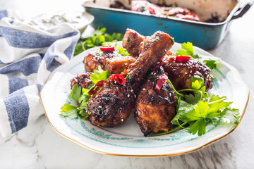 Grilled roasted and barbecue chicken legs on white plate.