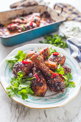 Grilled roasted and barbecue chicken legs on white plate.