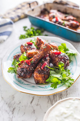 Grilled roasted and barbecue chicken legs on white plate.