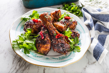 Grilled roasted and barbecue chicken legs on white plate.