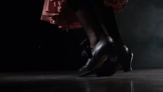 Legs of the girl are tap dancing. Light from behind. Smoke background. Close up. Slow motion