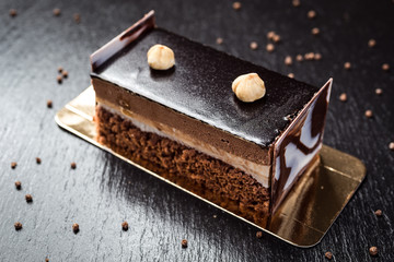 Dark chocolate vegan cake with candies and nuts on wooden background