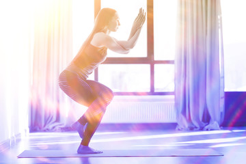 Fototapeta na wymiar gymnasium, yoga classes / a girl engaged in yoga, a trom in a large gym, light and rays of the sun. concept of yoga for women