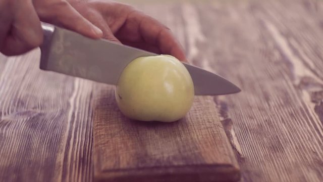 Man's hands cutting the apple on wooden board