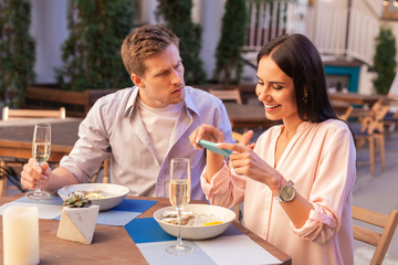 Furious man. Blonde-haired man feeling really furious sitting near blogger making photos of her food during date
