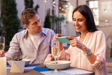 Surprised man. Handsome man feeling surprised while girlfriend taking pictures of her food during date