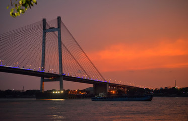 Silhouette of Vidyasagar setu bridge over river ganges at sunset.