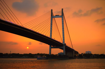 Silhouette of Vidyasagar setu bridge over river ganges at sunset.