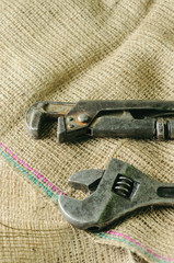 Two old adjustable wrench on a natural fabric background.