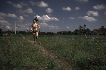 athletic runner Asian woman training running series workout working hard outdoors on field background in harsh contrast light sport advertising style