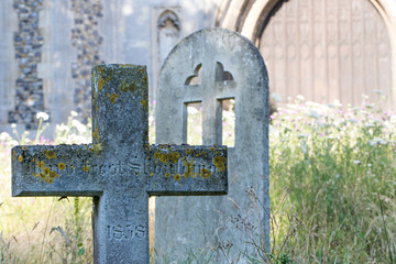 English country cemetary with ancient stone cross headstone in rural churchyard