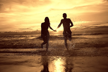 lovers run along the beach / guy and girl run along the summer sea beach, rest on the sea honeymoon