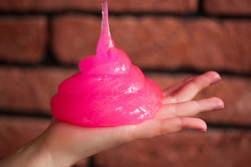 a toy for children mucus and liquid flowing on hand on background of a brick wall