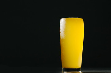 Glass beer with foam on black background with copyspace