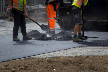 Baustelle: Bauarbeiter mit Schaufel bei der Asphaltfertigung