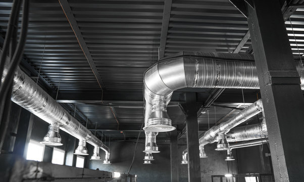 Ventilation system on the ceiling of large buildings. Ventilation pipes in silver insulation material hanging from the ceiling inside new building.