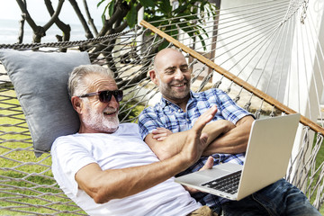Senior men lying on a hammock using a laptop