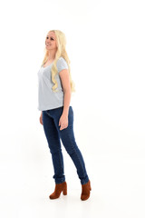 full length portrait of blonde girl wearing simple blue shirt and jeans, standing pose. isolated on white background.