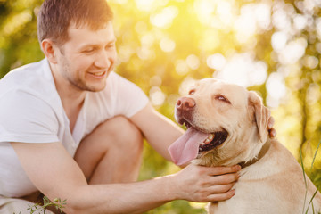Owner man caressing smile gently labrador dog outdoors in sunset. Concept friendship