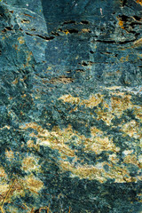 Texture of granite stone. Natural mountain stone. Blue shades of texture. The combination of turquoise and yellow on the rough surface of the stone