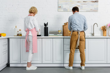 back view of grey hair couple cooking together at kitchen