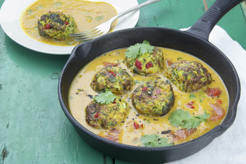 Courgette and chilli peppers fritters in vegetable sauce topped with coriander 