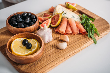 close-up view of delicious snacks on wooden board on table