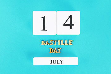 wooden calendar on a blue background. The concept of the holiday is July 14, the Day of the Bastille.